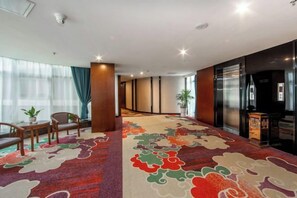 A hotel lobby with a carpeted floor, seating area, and a reception desk. - Sanjianghe International Hotel (Pingle)