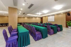 A conference room with rows of tables and chairs, a projector screen, and a large plant. - Sanjianghe International Hotel (Pingle)