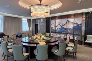A conference room with a round table, chairs, a chandelier, artwork on the walls, and a view of the outdoors. - Sanjianghe International Hotel (Pingle)