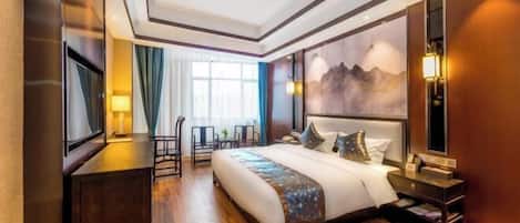 Habitación de hotel con una cama grande, un escritorio, una silla, un televisor y un cuadro en la pared.
