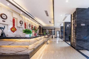 A hotel lobby with a marble reception desk, decorative wall elements, and a modern design. - Sanjianghe International Hotel (Pingle)