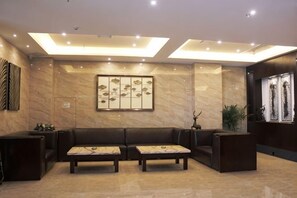 A lobby with a reception desk, seating area, and a wall-mounted artwork. - Sanjianghe International Hotel (Pingle)