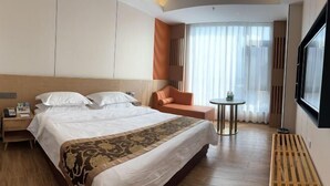 A hotel room with a large bed, a small round table, a chair, a TV, and a window with curtains. - Suofeike Hotel (Pinghe)