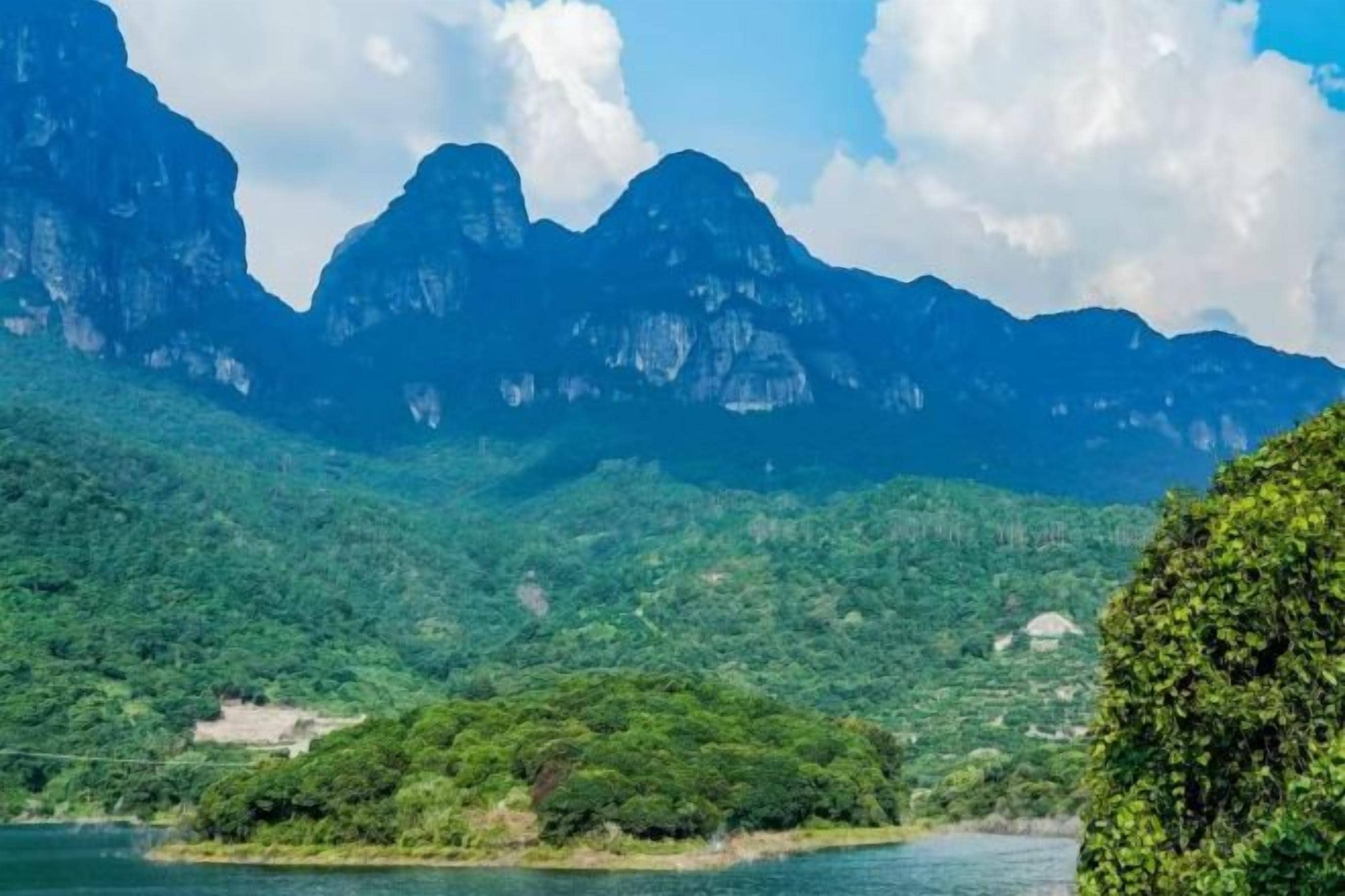 Un paysage montagneux avec une étendue d’eau au premier plan et un ciel dégagé.