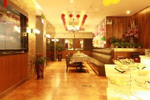Vestíbulo de hotel con mostrador de recepción, zona de estar y mesa de buffet.