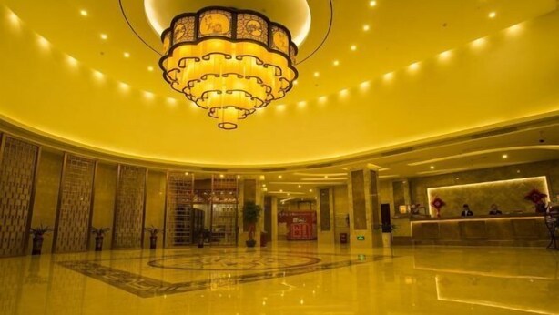 A spacious lobby with a large chandelier, a reception desk, and a polished floor. - Suofeike Hotel (Pinghe)