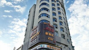 A tall building with a large digital billboard displaying advertisements. - Suofeike Hotel (Pinghe)