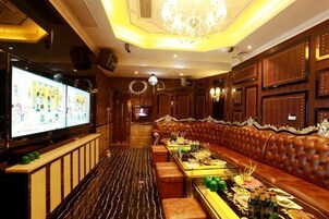 Un área de bar con un largo banco de madera, una pantalla de televisión y una araña.