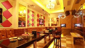 A bar area with a long counter, cushioned seating, and a television screen.