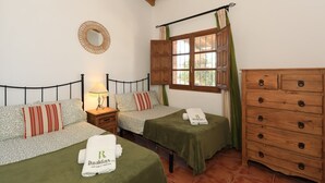 Un dormitorio con dos camas, un aparador de madera, una ventana con cortinas y un espejo montado en la pared.