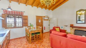 Una sala de estar acogedora con un sofá rojo, una mesa de comedor de madera y una chimenea.