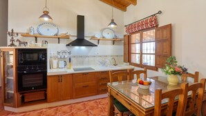 Una cocina con armarios de madera, un horno negro, un fregadero y una mesa de comedor con sillas.
