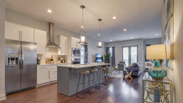 A modern kitchen with a central island, stainless steel appliances, and a dining area with bar stools. - Beautiful Nashville Home – Near Broadway (Nashville)