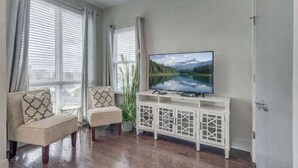 A living room with a sofa, armchair, TV, and a cabinet. - Beautiful Nashville Home – Near Broadway (Nashville)