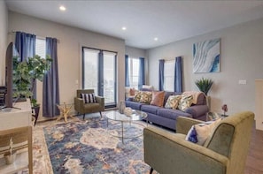 Een woonkamer met een bank, fauteuils, een bijzettafeltje en een vloerkleed.
