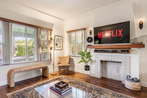 A living room with a fireplace, a large TV mounted above it, and a bench.