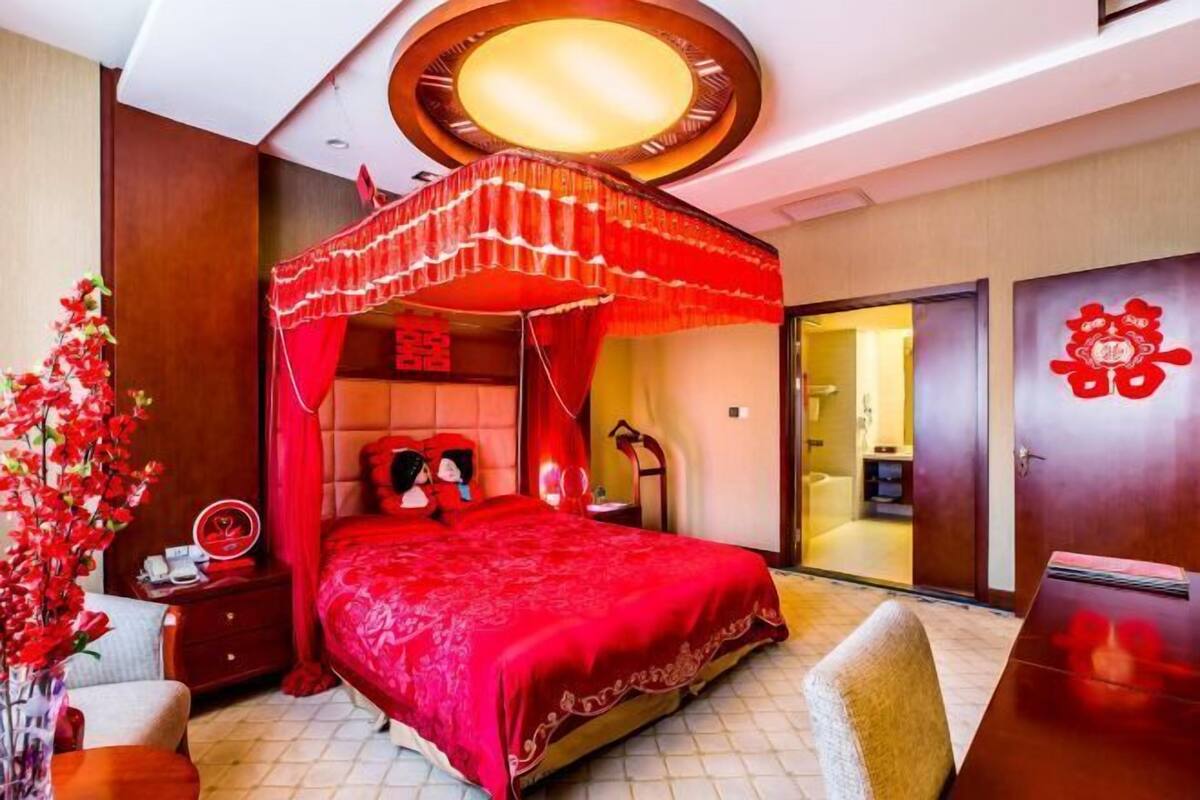 A room with a bed, a nightstand, a chair, a desk, and a wardrobe.