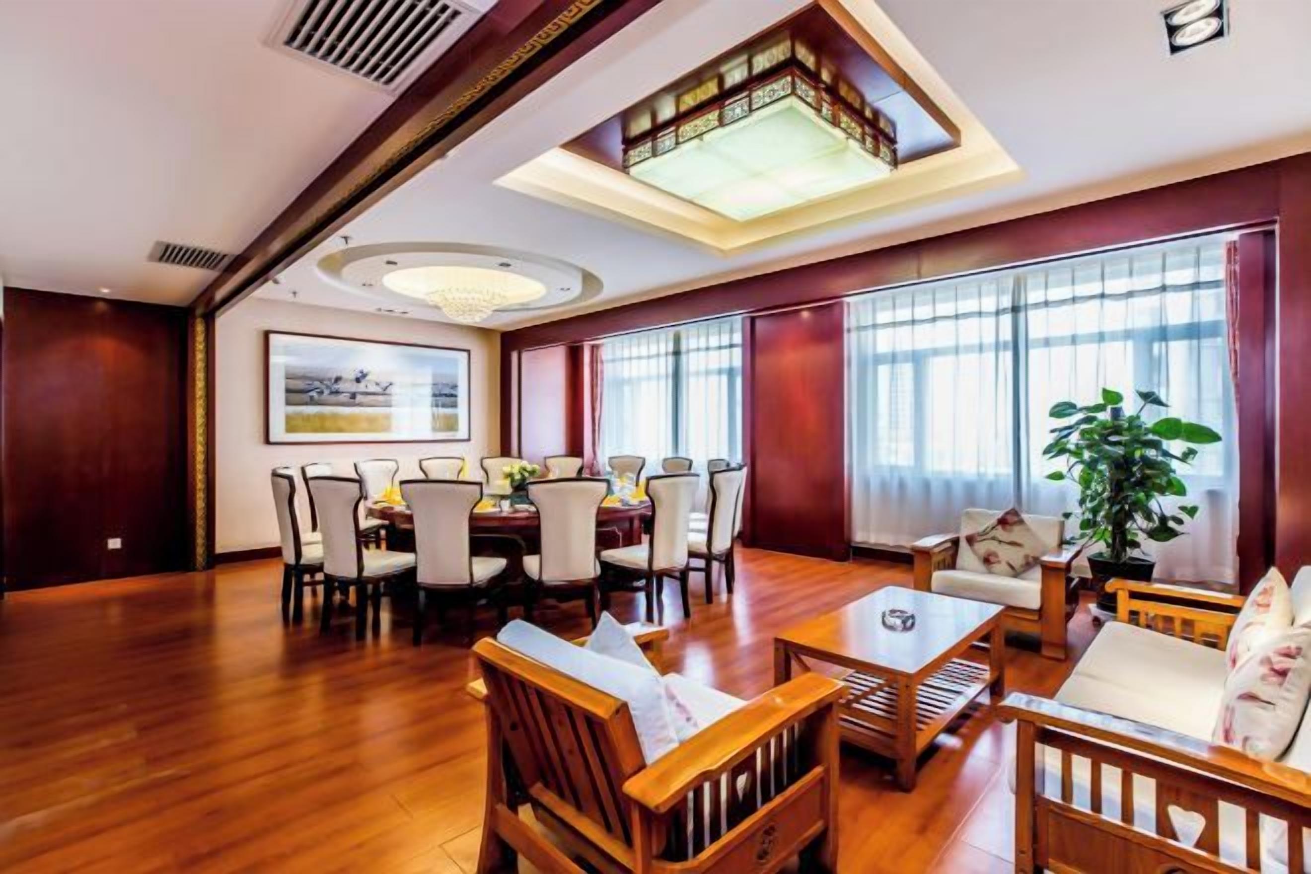 A spacious room with a dining area, a seating area with a coffee table, and large windows with curtains.