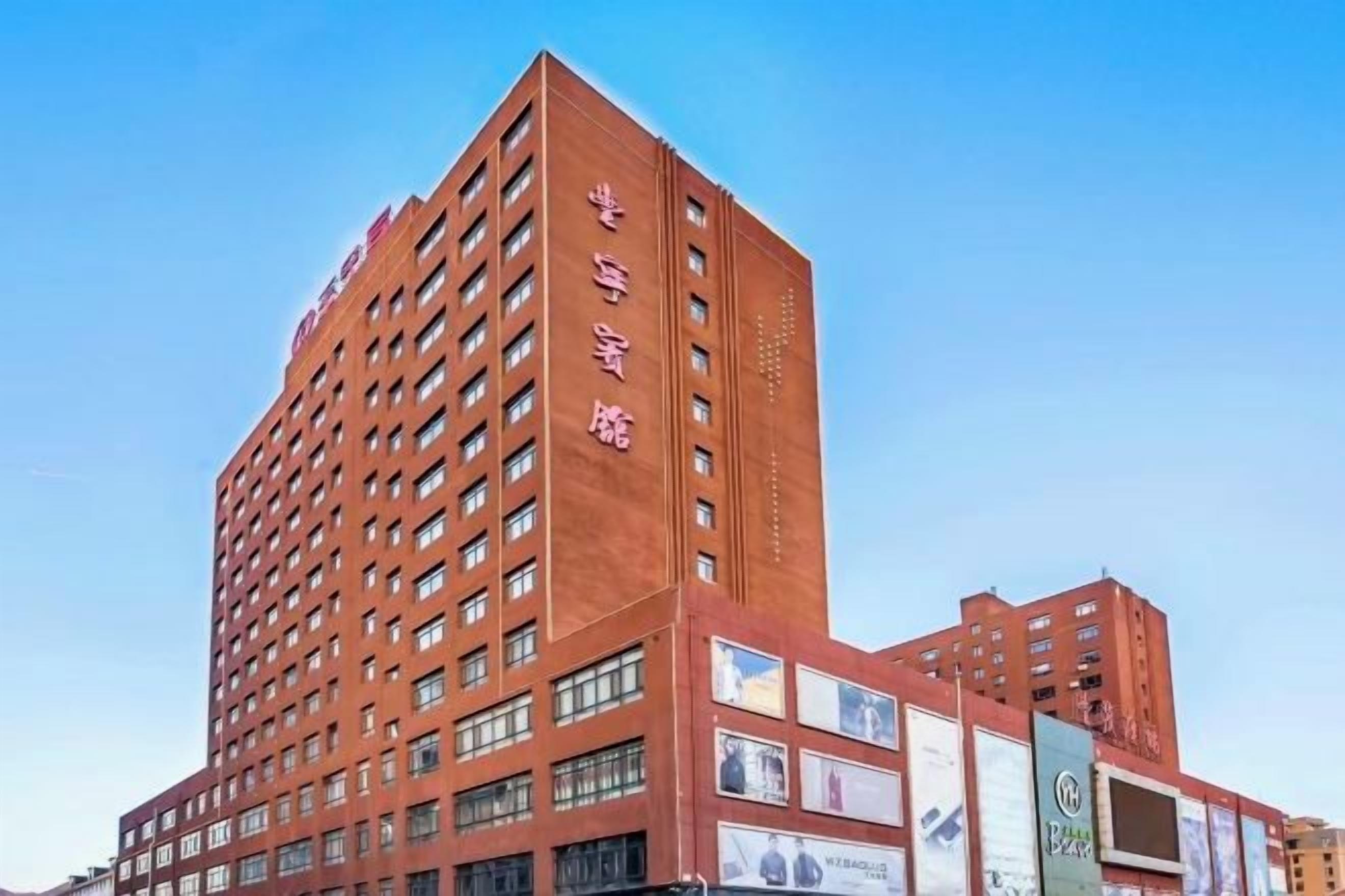 A multi-story hotel with a red facade, numerous windows, and several large billboards.