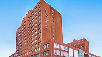 A multi-story hotel with a red facade, numerous windows, and several large billboards.