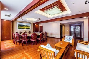 Un comedor con una gran mesa redonda y sillas, un sofá y piso de madera.