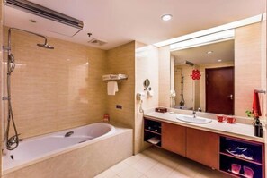 Un baño moderno con bañera, un espejo grande y tocador con lavamanos y toallero.
