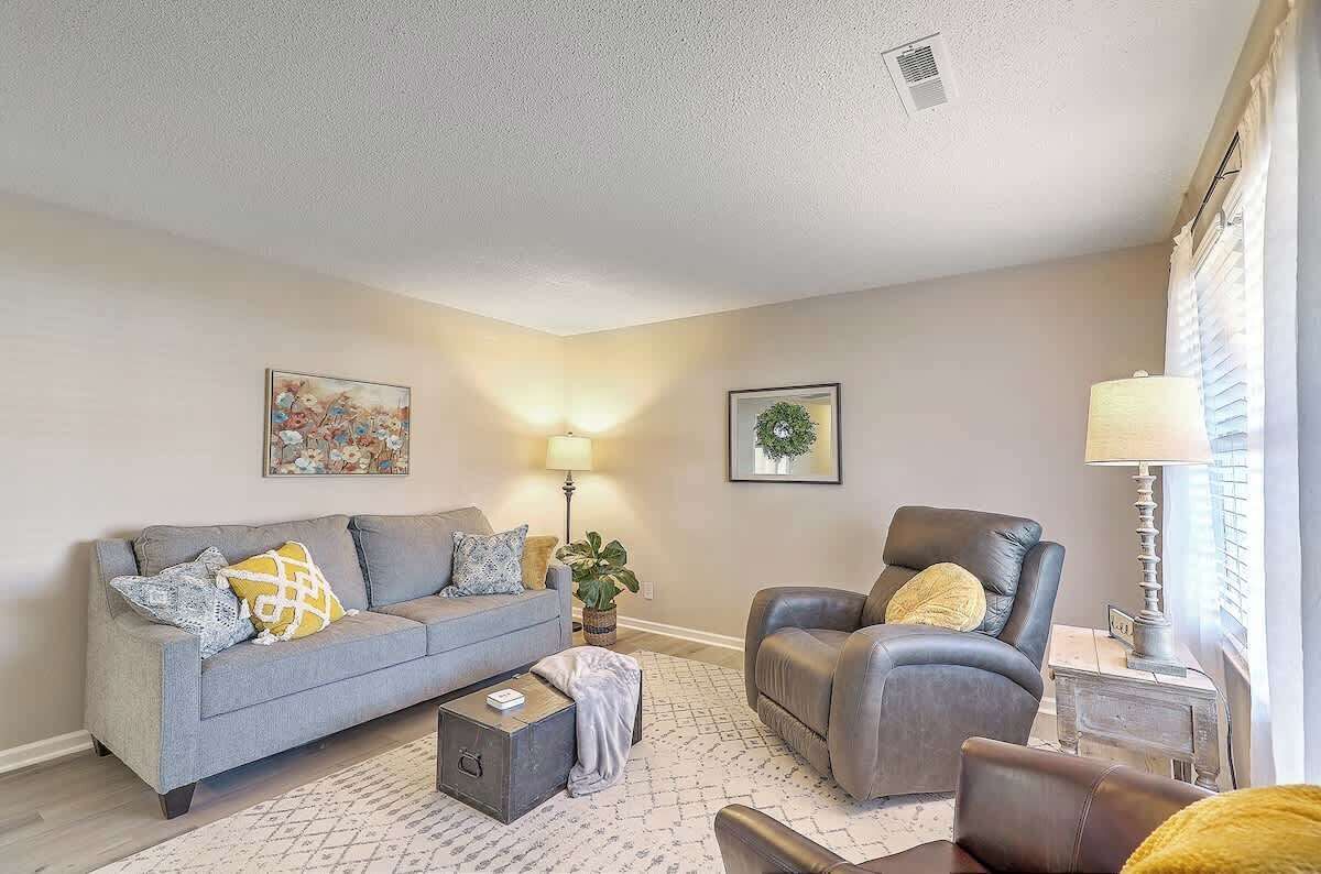 Un salon avec un canapé gris, un fauteuil en cuir, une petite table et une lampe.