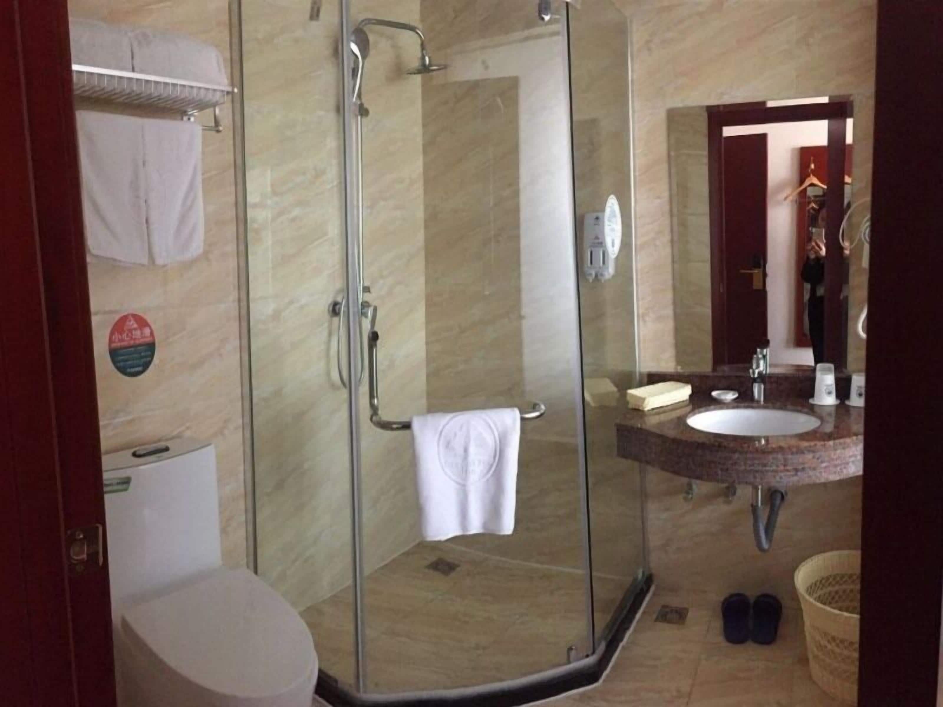 A bathroom with a glass-enclosed shower, a toilet, a sink with a vanity, and a mirror.
