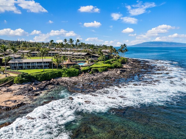 A coastal resort with multiple buildings, a swimming pool, and a rocky shoreline. - Cozy Studio Steps to Sandy Beach - Napili Shores D126 (Lahaina)