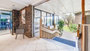 Una entrada de hotel moderna con un muro de piedra, una escalera de madera y vistas al área exterior.