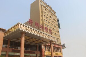 Un hotel con una entrada destacada, fachada decorativa y un letrero grande.