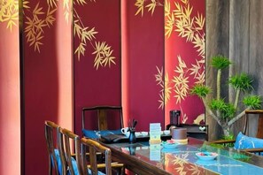 A dining area with a glass table, chairs, and a decorative wall with a bamboo pattern. - Tang Dynasty Hotel (Ningjin)