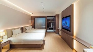 A hotel room with two beds, a TV, a wardrobe, and a mirror. - Tang Dynasty Hotel (Ningjin)