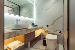 A modern bathroom with a large white sink, a mirror, a towel rack, and a trash can.