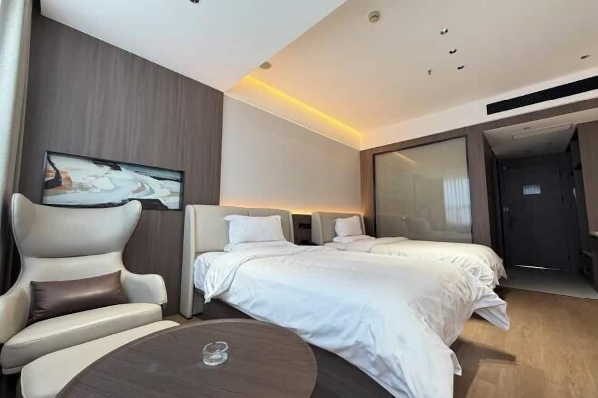 A modern hotel room with a bed, a seating area, and a painting on the wall.