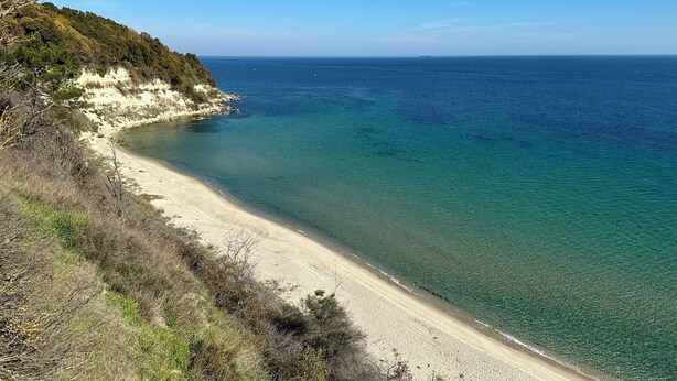 A coastal landscape with a sandy beach, clear blue water, and a hilly terrain with sparse vegetation. - Top floor private app sea & city view Balcony barbecue. Best location Chayka.  (Varna)