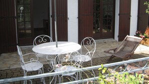 Un patio al aire libre con una mesa redonda y cuatro sillas, rodeado por una valla de metal.