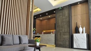 A modern reception area with a sofa, a small table with flowers, and a reception desk. - Jinjiang Inn Select (Xuzhou High-speed Railway Huaihai Huanqiugang) (Xuzhou)