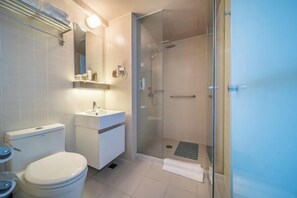 A modern bathroom with a toilet, sink, and glass-enclosed shower.