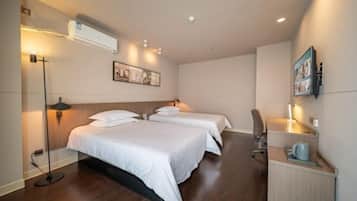 Habitación de hotel con dos camas, un escritorio, una silla y una pequeña kitchenette.