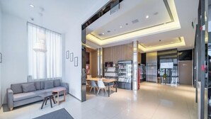 A modern living room with a sofa, coffee table, and dining area. - Jinjiang Inn Select (Xuzhou High-speed Railway Huaihai Huanqiugang) (Xuzhou)