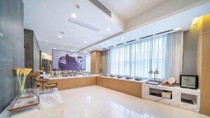 A spacious, modern hotel lobby with a large seating area, a reception desk, and a large screen displaying a person. - Jinjiang Inn Select (Xuzhou High-speed Railway Huaihai Huanqiugang) (Xuzhou)