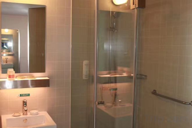 A modern bathroom with a glass-enclosed shower, a sink with a mirror, and a towel rack.