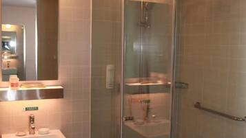 A modern bathroom with a glass-enclosed shower, a sink with a mirror, and a towel rack.