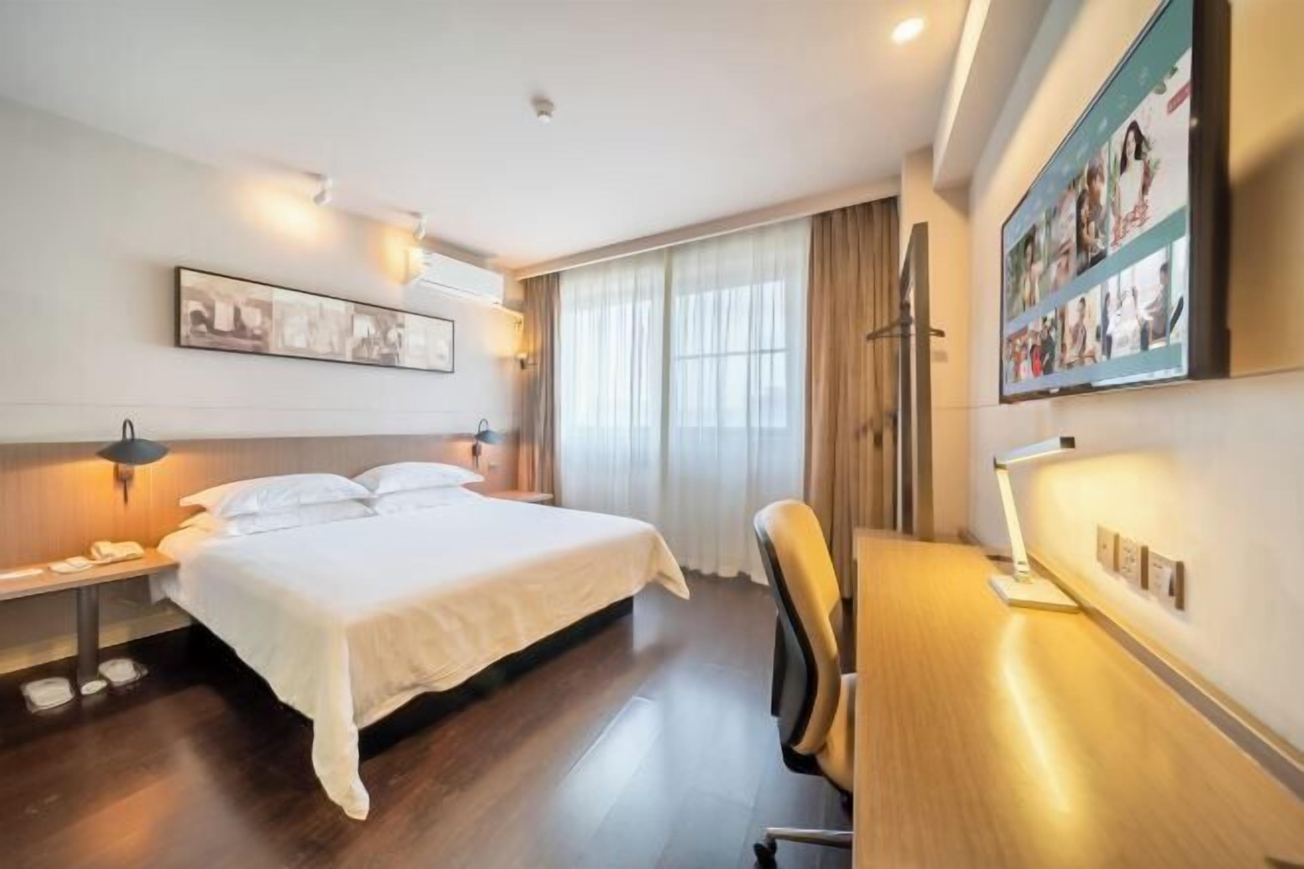 Ein Hotelzimmer mit Bett, Nachttisch, Lampe und Schreibtisch mit Stuhl.