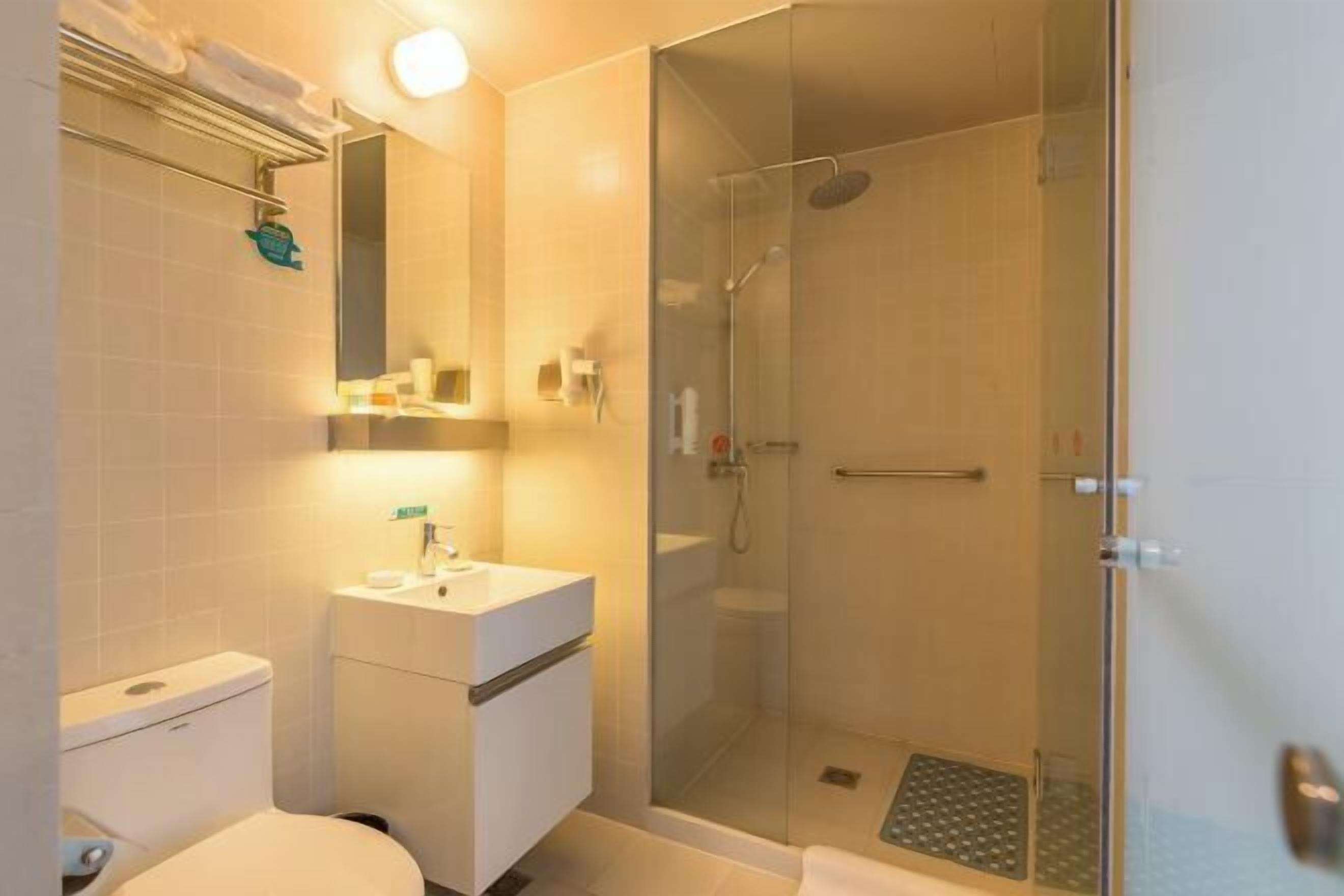 Ein modernes Badezimmer mit einer gläsernen Dusche, einem weißen Waschbecken und einer Toilette.