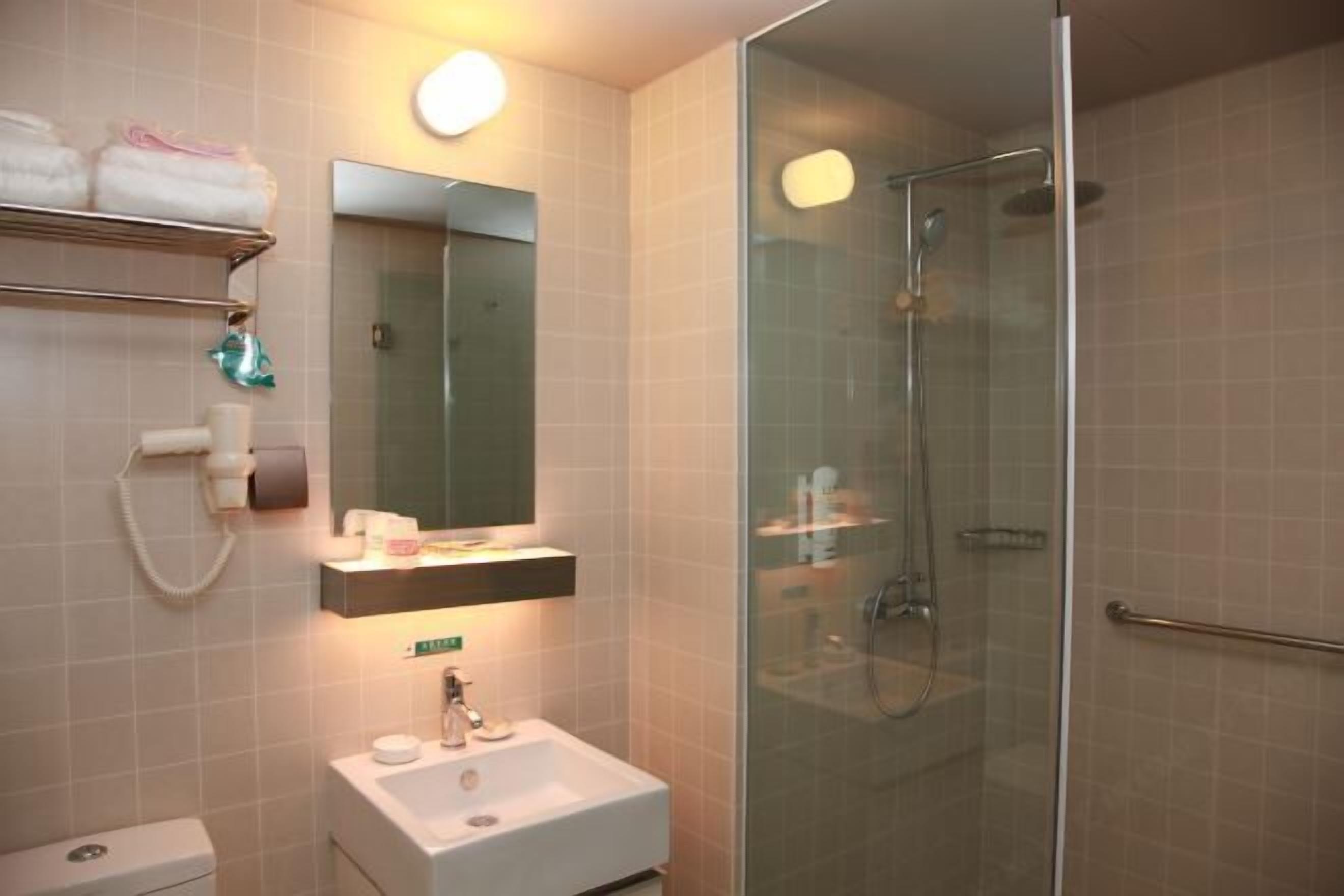 A bathroom with a glass-enclosed shower, a sink, a mirror, and a towel rack.