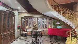 A grand foyer with a staircase, a red table, and a cabinet with glass doors. - Shanghai Jiu Yu Hotel (Shanghai)
