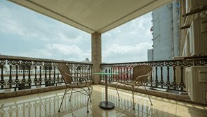 A balcony with a table and chairs, a railing, and a view of buildings. - Shanghai Jiu Yu Hotel (Shanghai)