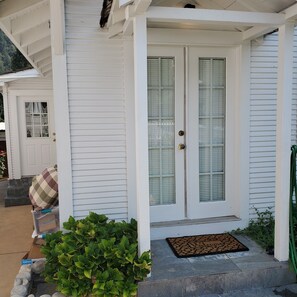 A white house with a front door, a porch, and a welcome mat.